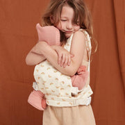 A rainbow-patterned Olli Ella Doll Carrier with padded straps designed for carrying dolls.